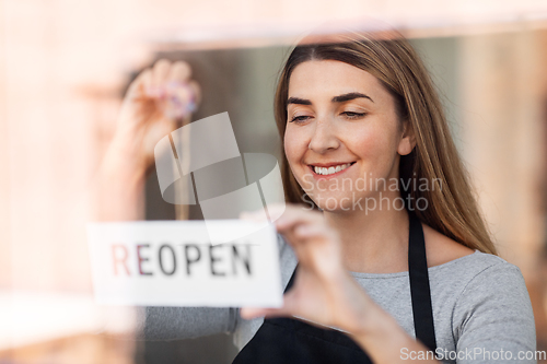 Image of happy woman hanging reopen banner to door glass