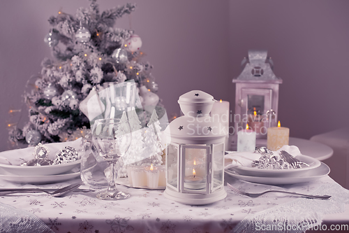 Image of Festive  Christmas table place setting with silverware, candles 