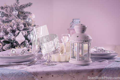 Image of Festive  Christmas table place setting with silverware, candles and decorated Christmas tree
