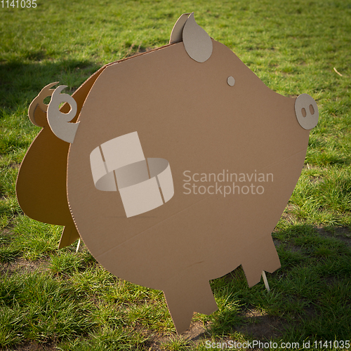 Image of Cardboard pig on a green grass. Creative decoration.