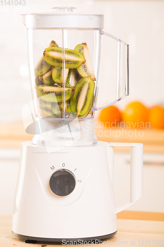 Image of Young man cooking kiwi smoothie in blender