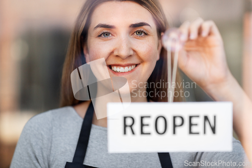 Image of happy woman hanging reopen banner to door glass