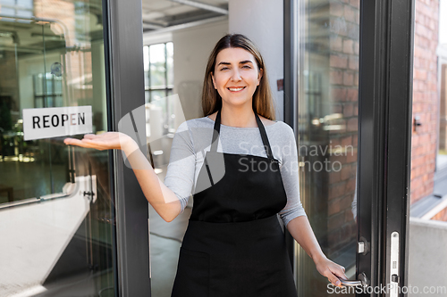 Image of happy woman showing reopen banner on door glass