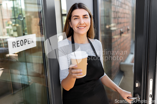 Image of happy woman with coffee and reopen banner on door