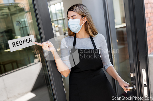 Image of woman in mask showing reopen banner on door glass