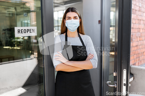 Image of woman in mask with reopen banner on door glass