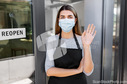 Image of woman in mask with reopen banner on door glass
