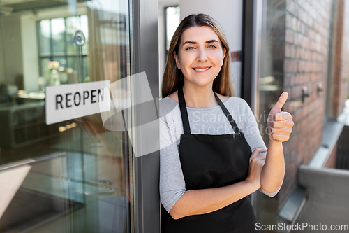 Image of woman with reopen banner on door showing thumbs up