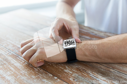 Image of male hands with qr code on smart watch