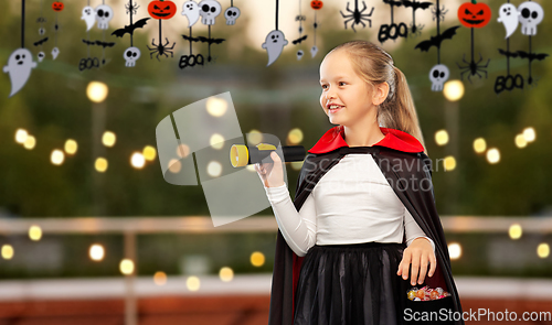 Image of girl in halloween costume of dracula with candies