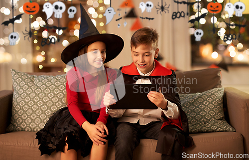 Image of kids in halloween costumes with tablet pc at home