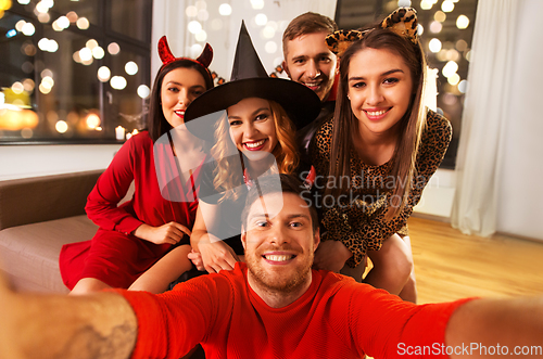 Image of happy friends in halloween costumes taking selfie