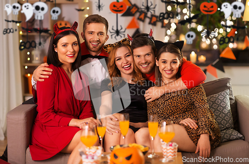 Image of happy friends in halloween costumes at home party