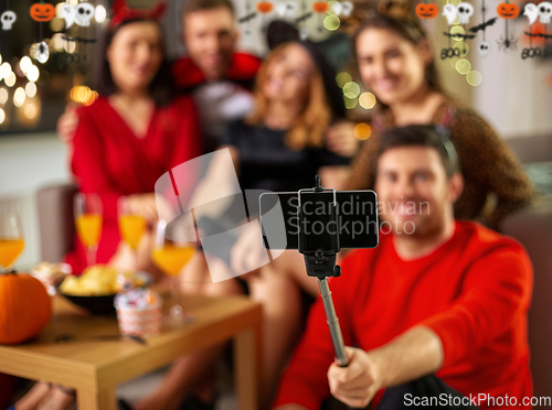 Image of happy friends in halloween costumes taking selfie