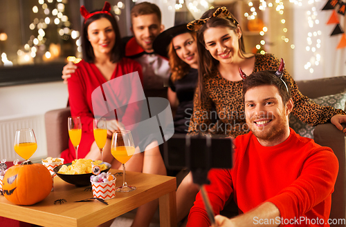 Image of happy friends in halloween costumes taking selfie