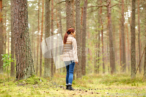 Image of asian woman picking mushrooms in autumn forest