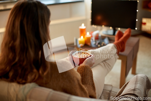 Image of woman watches tv and drinks cocoa on halloween