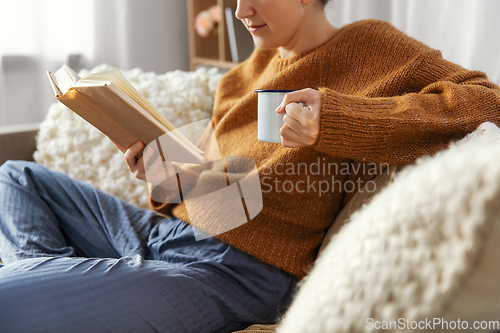 Image of woman drinking coffee and reading book at home