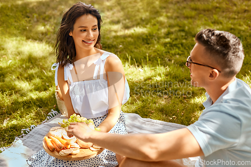 Image of happy couple having picnic at summer park