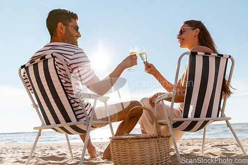 Image of happy couple drinking champagne on summer beach