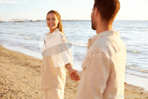 Image of happy couple holding hands on summer beach