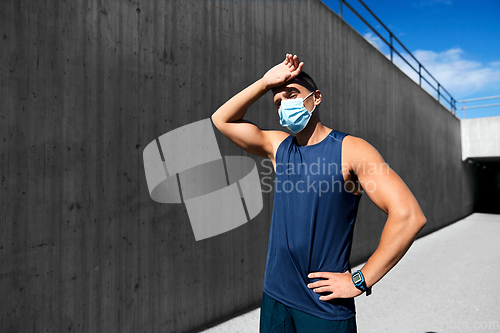 Image of tired man in medical mask doing sports outdoors