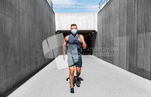 Image of young man in medical mask running outdoors