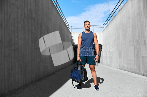 Image of sportsman with bag and bottle walking outdoors