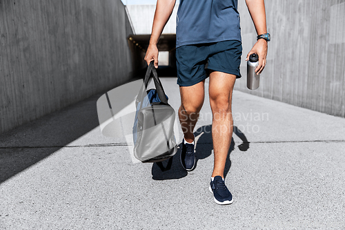 Image of sportsman with bag and bottle walking outdoors