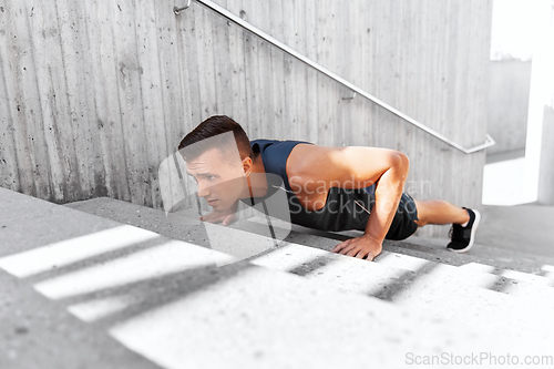 Image of young man doing push ups on stairs outdoors