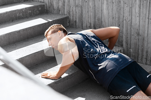 Image of young man doing push ups on stairs outdoors