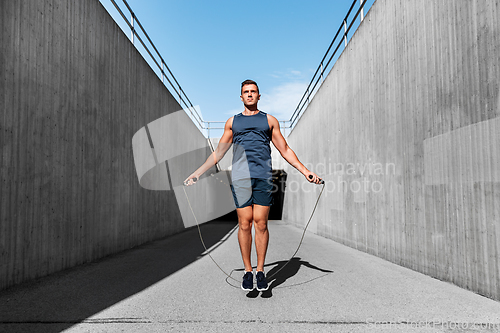 Image of man exercising with jump-rope outdoors