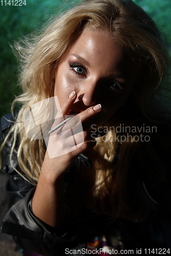 Image of Young woman smoking in night park