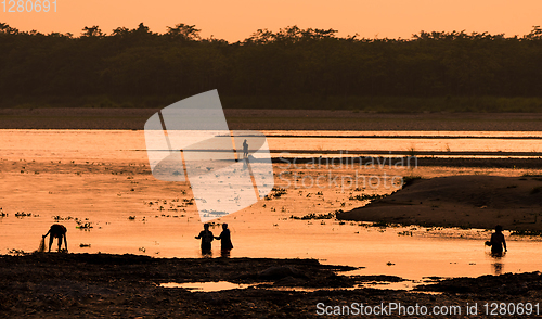 Image of Asian women fishing in the river, silhouette at sunset