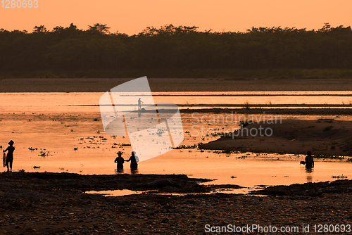 Image of Asian women fishing in the river, silhouette at sunset