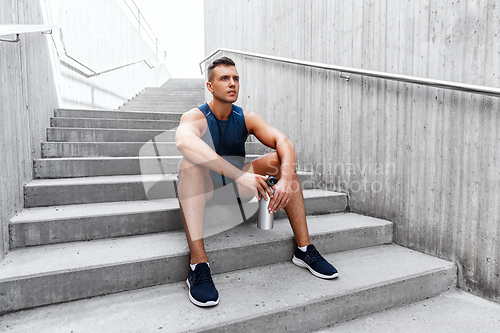 Image of sportsman with bottle sitting on city bench