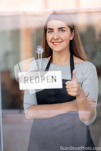 Image of happy woman hanging reopen banner to door glass