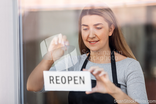 Image of happy woman hanging reopen banner to door glass