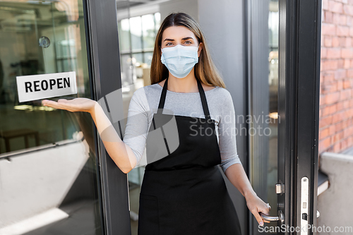 Image of woman in mask showing reopen banner on door glass