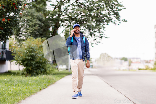 Image of indian delivery man with bag calling on smartphone