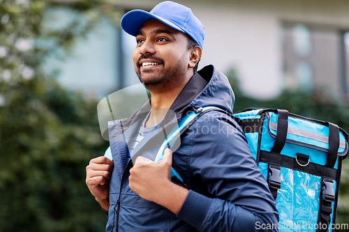 Image of happy smiling indian delivery man with bag in city