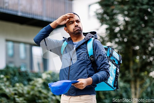 Image of tired indian delivery man with bag in city