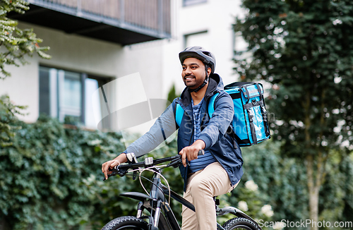 Image of indian delivery man with bag riding bicycle