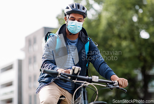 Image of delivery man in mask with smatphone riding bicycle