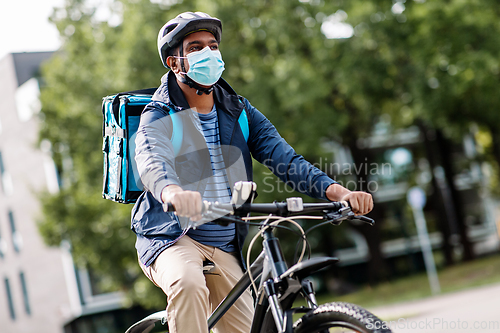 Image of delivery man in mask with smatphone riding bicycle