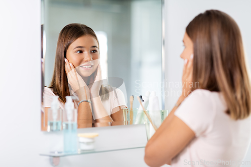 Image of teenage girl looking in mirror at bathroom