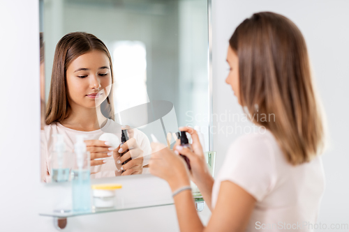 Image of teenage girl applying lotion to cotton disc