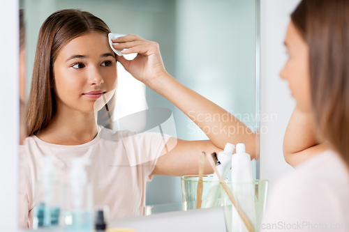 Image of teenage girl cleaning face skin with cotton disc