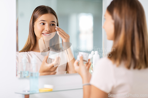 Image of teenage girl with moisturizer at bathroom