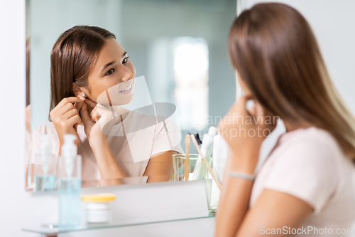 Image of teenage girl with earring looking in mirror